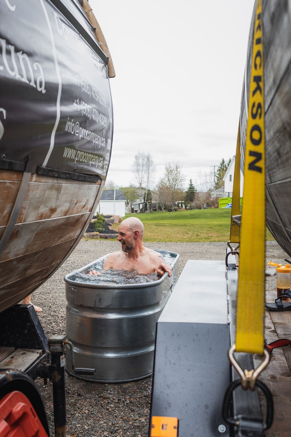 A member taking a cold plunge between sauna barrels at a DrivenDad retreat