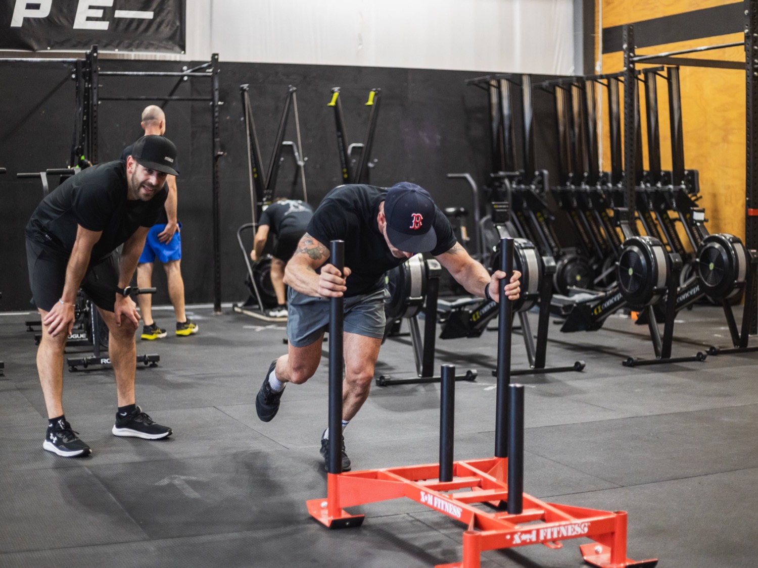 Entrepreneur fathers pushing sleds in a group workout at the gym